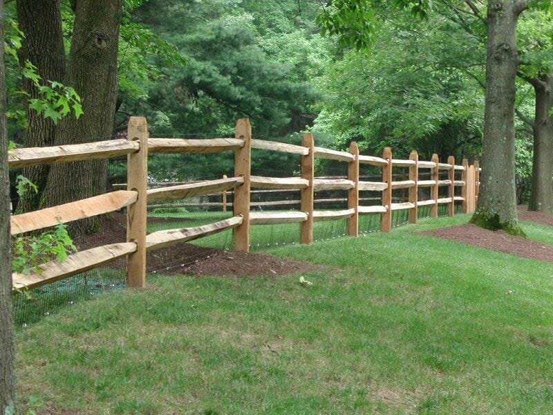 post and rail fence between trees large property